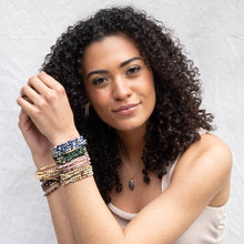 Load image into Gallery viewer, Woman with curly hair wearing multiple bracelets on a light background