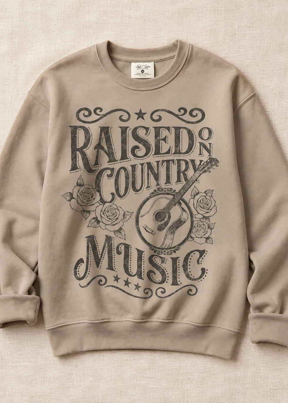 light mocha sweatshirt with country music screen print design laying on beige back drop
