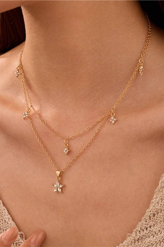Close-up of a person wearing a gold necklace with floral pendants.