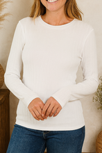 Load image into Gallery viewer, Woman wearing a white long-sleeve shirt and blue jeans standing in a room with decorative vases and plants.