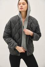 Load image into Gallery viewer, Person wearing a gray quilted jacket with a hood on a plain background