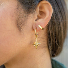 Load image into Gallery viewer, Close-up of a person wearing a gold hoop earring with a star-shaped pendant.