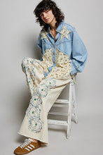 Load image into Gallery viewer, Person wearing a floral-patterned outfit with a denim jacket, sitting on a stool against a plain background.