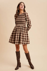 Woman wearing a plaid dress with long sleeves on a beige background