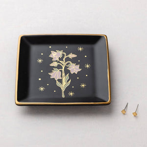 Black square dish with gold floral design on a light gray background