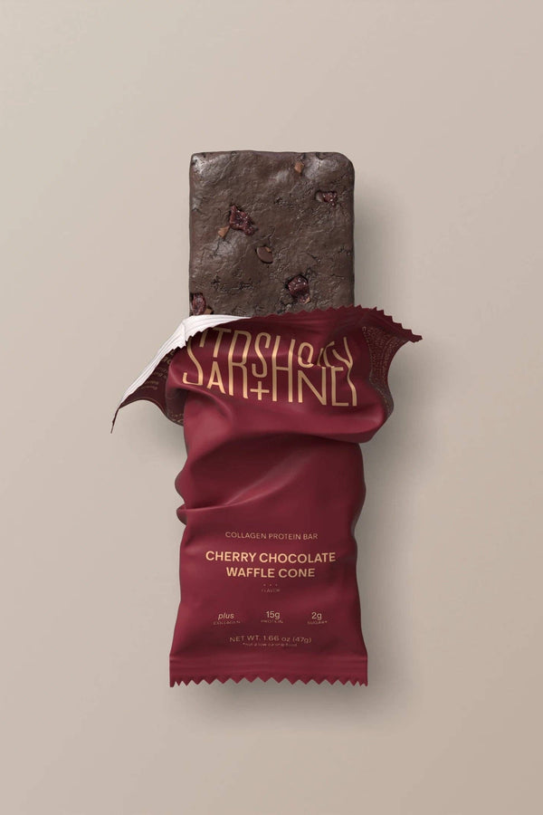 Chocolate protein bar with cherry chocolate waffle cone flavor packaging on a beige background