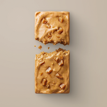 Load image into Gallery viewer, Two square pieces of cookie with a peanut butter filling on a beige background