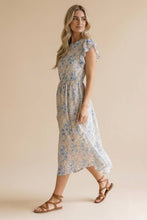 Load image into Gallery viewer, Woman wearing a floral dress against a beige background