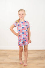 Load image into Gallery viewer, Young girl wearing a red, white, and blue checkered outfit on a wooden floor with a white background