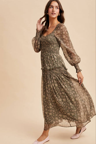 Woman wearing a long, patterned dress against a beige background
