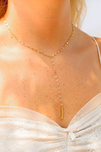 Load image into Gallery viewer, Gold necklace with a pendant worn by a person against a blurred background