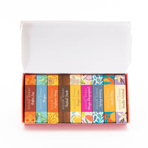 Box of colorful room spray bottles with labels on a white background