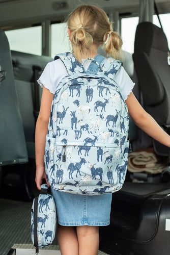 Child with a blue animal-patterned backpack and smaller bag inside a vehicle.