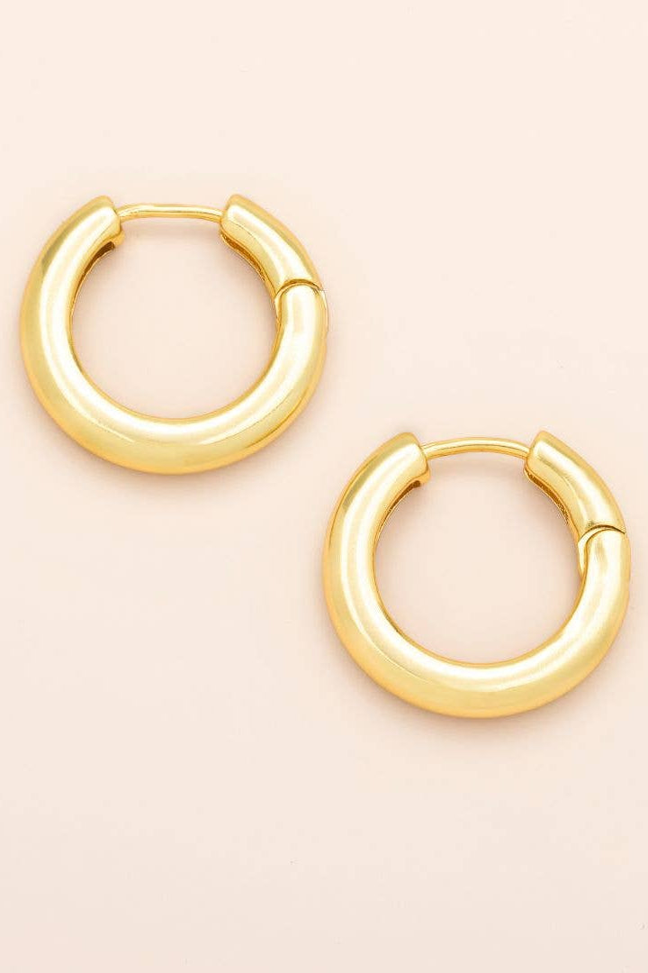 Gold hoop earrings on a beige background