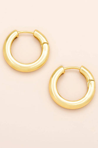 Gold hoop earrings on a beige background