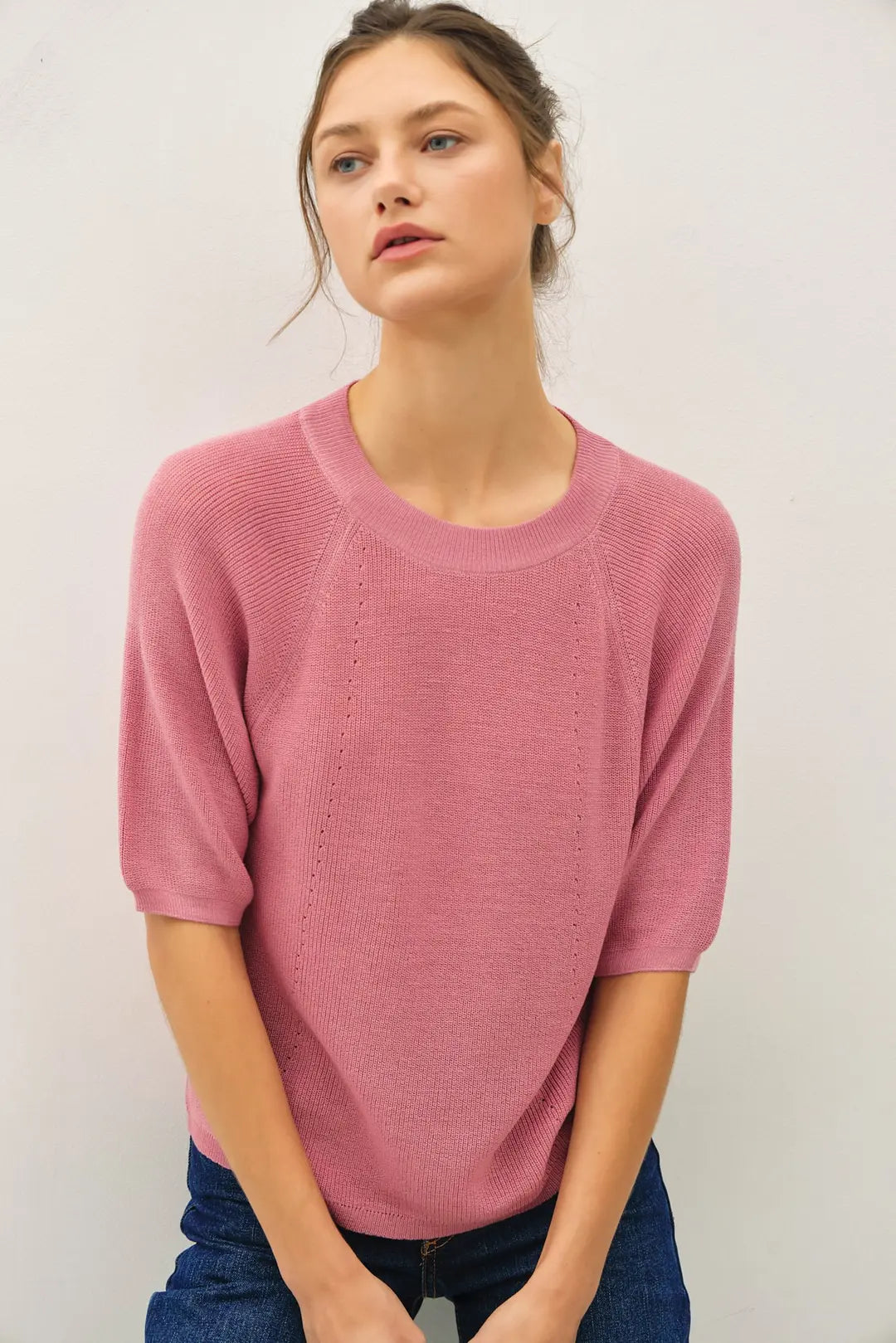 Woman wearing a pink sweater against a plain background