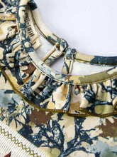 Load image into Gallery viewer, Close-up of a patterned fabric with a visible brand label on a white background