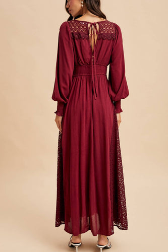 Woman wearing a burgundy dress with lace details on a beige background