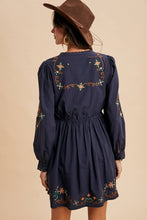 Load image into Gallery viewer, Navy blue dress with floral embroidery worn by a person against a beige background