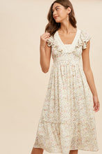 Load image into Gallery viewer, Woman wearing a floral dress against a beige background