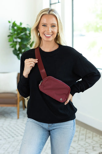 girl wearing black sweater and burgundy bum bag crossbody