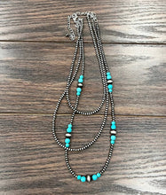 Load image into Gallery viewer, Multistrand necklace with turquoise beads on a wooden surface
