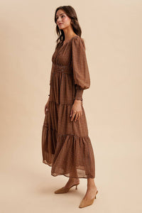 Woman wearing a brown patterned dress on a beige background