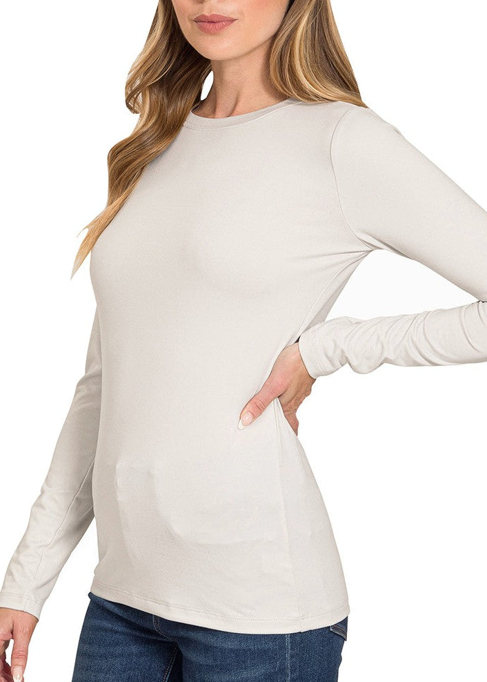 Woman wearing a beige long-sleeve top with a plain background