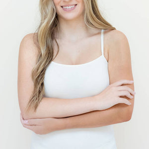 Woman wearing a white tank top with a plain background