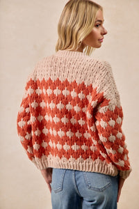 Person wearing a patterned sweater with a neutral background