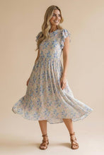 Load image into Gallery viewer, Woman wearing a floral dress against a beige background