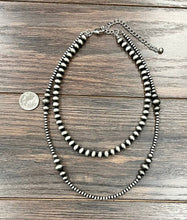 Load image into Gallery viewer, Necklace with beads on a wooden surface, next to a quarter for scale