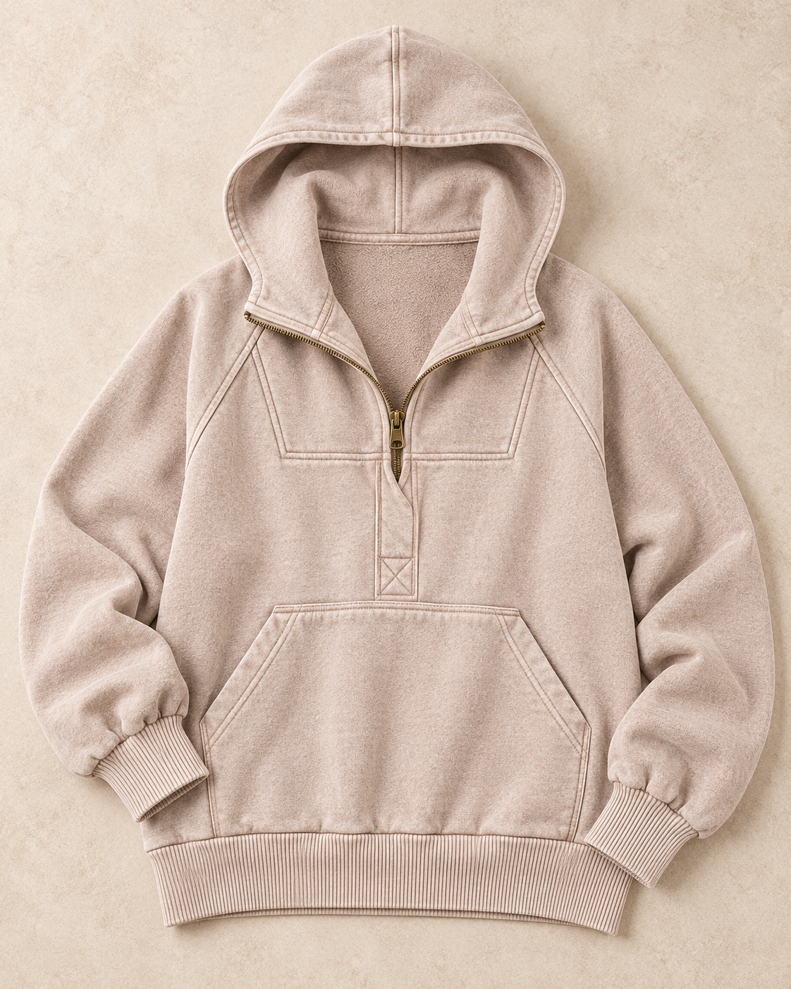 A light beige fleece pullover hoodie with a half-zip collar, ribbed cuffs, and a front kangaroo pocket, laid flat on a textured beige background.