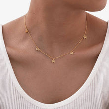 Load image into Gallery viewer, Gold necklace with small floral pendants on a person wearing a white top.