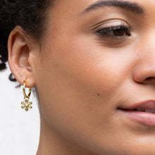 Load image into Gallery viewer, Close-up of a woman wearing a gold hoop earring with a floral design.