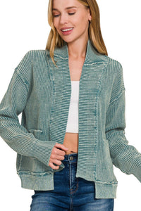 Woman wearing a textured green jacket with a white top and blue jeans on a white background