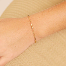 Load image into Gallery viewer, Gold bracelet on a person's wrist against a beige background