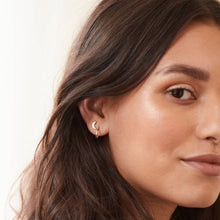 Load image into Gallery viewer, Close-up of a woman wearing a gold hoop earring with a neutral background