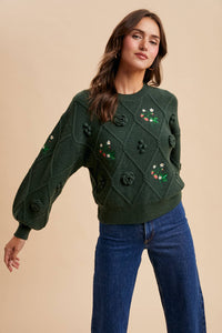 Woman wearing a green sweater with floral and rose patterns on a beige background