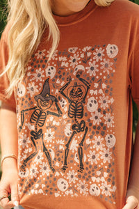 Person wearing an orange t-shirt with skeleton and floral design