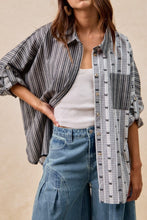 Load image into Gallery viewer, Woman wearing a plaid shirt over a white top and blue jeans on a beige background