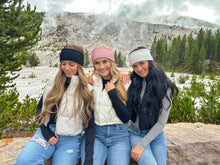 Load image into Gallery viewer, Three women posing together in a mountainous landscape with snow and trees.