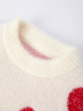 Load image into Gallery viewer, Close-up of a cream-colored sweater with red heart patterns on a light gray background