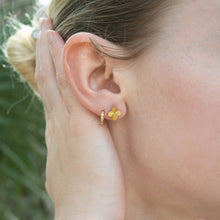 Load image into Gallery viewer, Close-up of a person wearing gold earrings with a blurred natural background