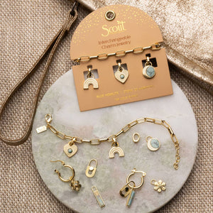 Scout interchangeable charm jewelry set on a marble surface with a beige card