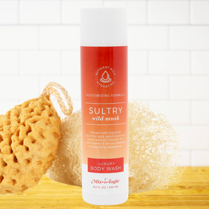 Body wash bottle labeled 'Sultry Wild Musk' with sponges on a white background