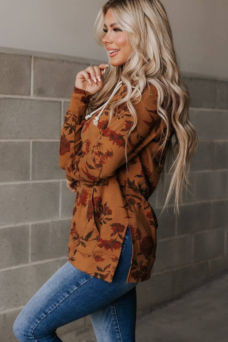 Woman wearing a floral patterned cardigan against a tiled wall.