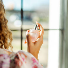 Load image into Gallery viewer, Person holding a pink perfume bottle with a blurred background