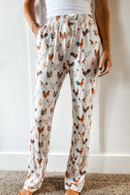 Load image into Gallery viewer, Person wearing pajama pants with chicken pattern against a white wall.