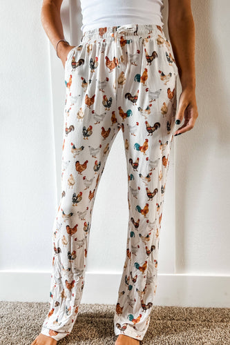 Person wearing pajama pants with chicken pattern against a white wall.